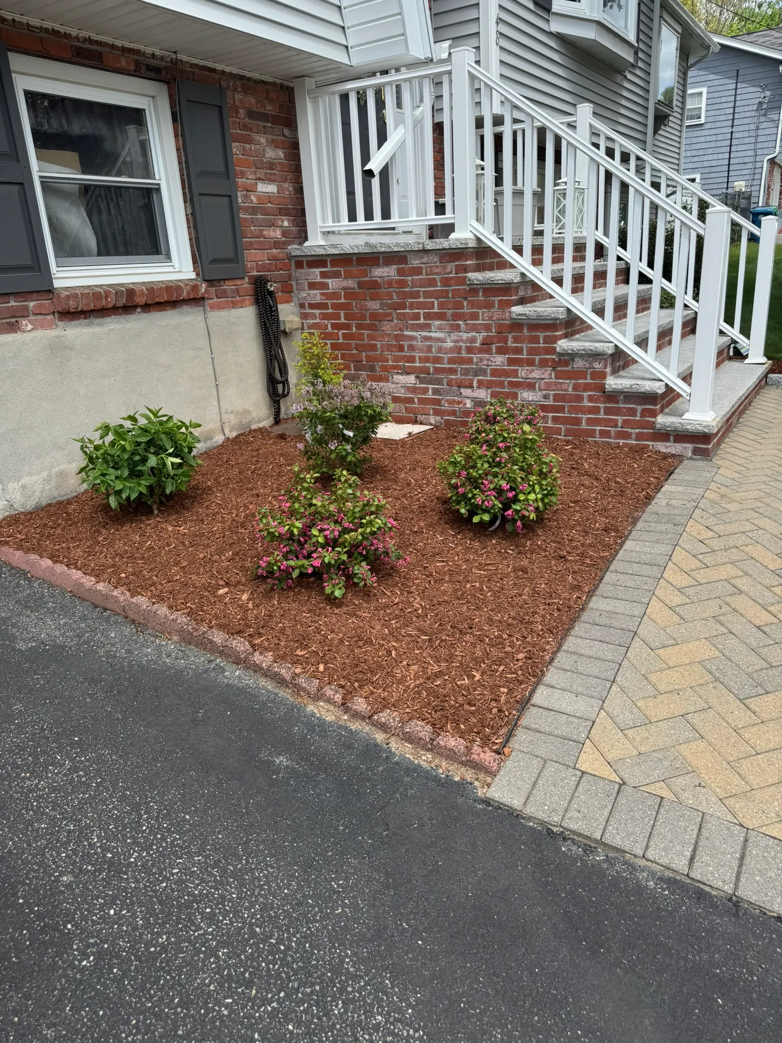 Brick front steps and a paver walkway beside a mulched planting bed