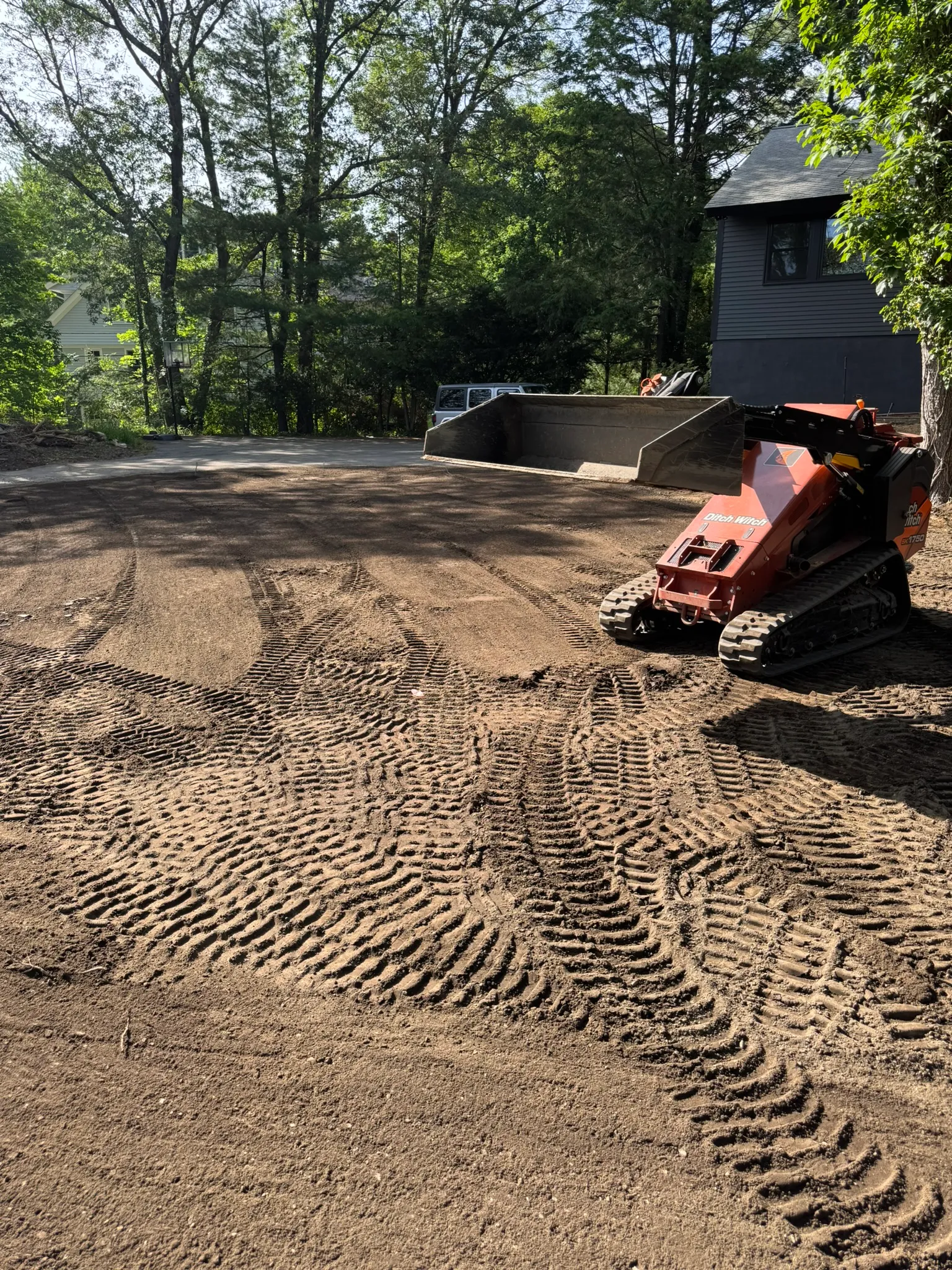 A freshly graded dirt yard with track marks after excavation work