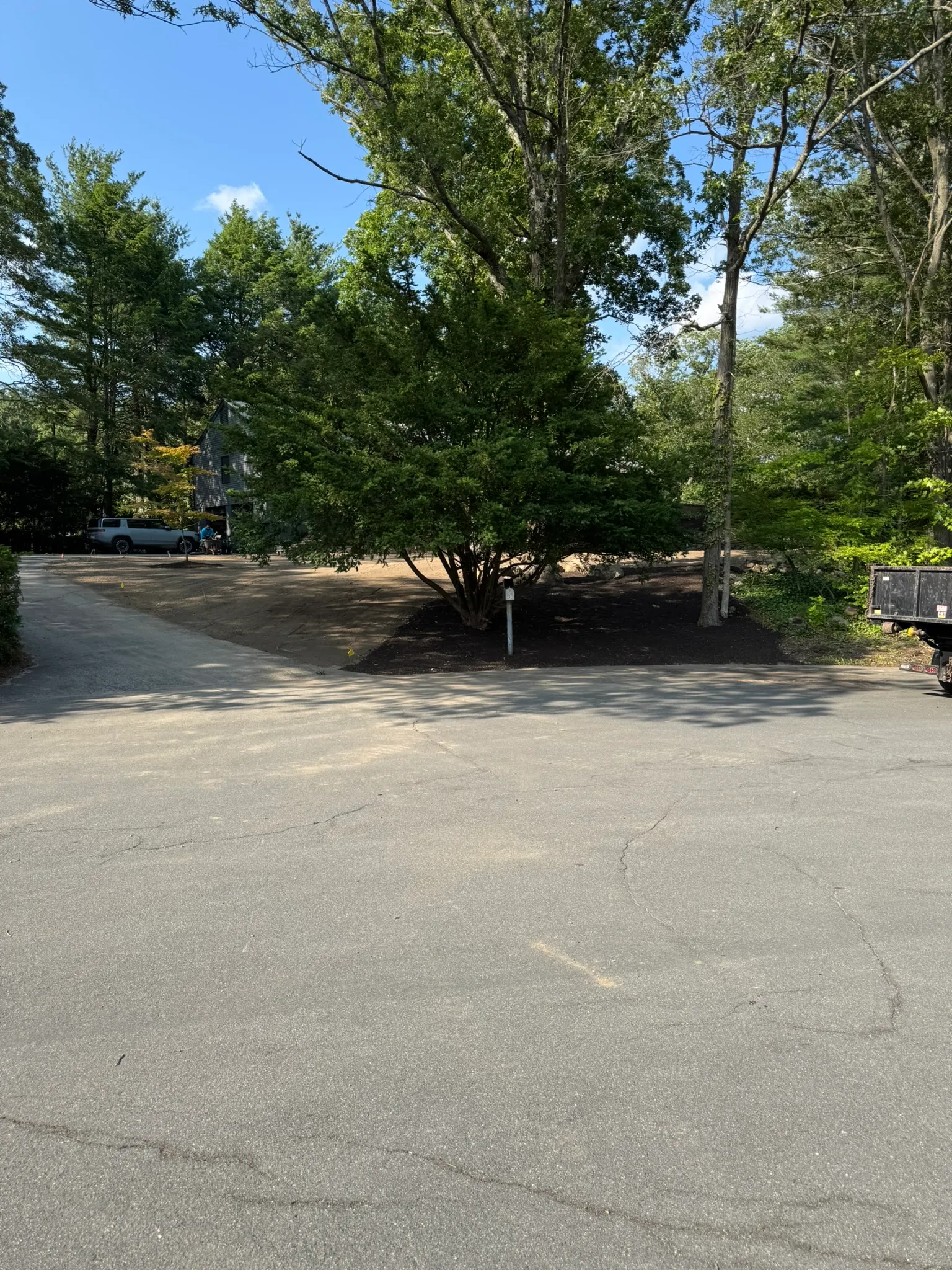A cleared and mulched grounds area beside a commercial parking lot
